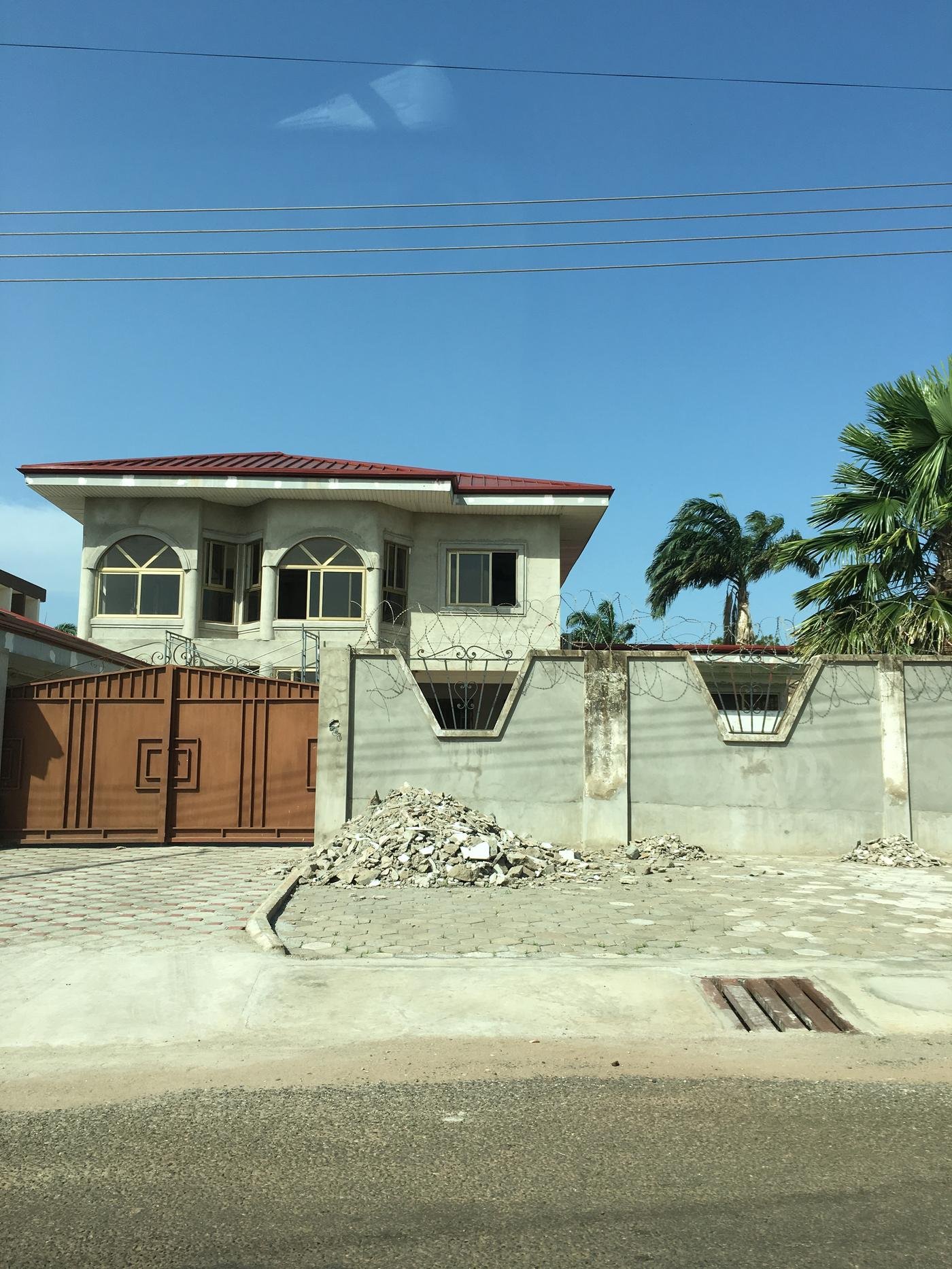 A diaspora-funded house mid-build behind its gate