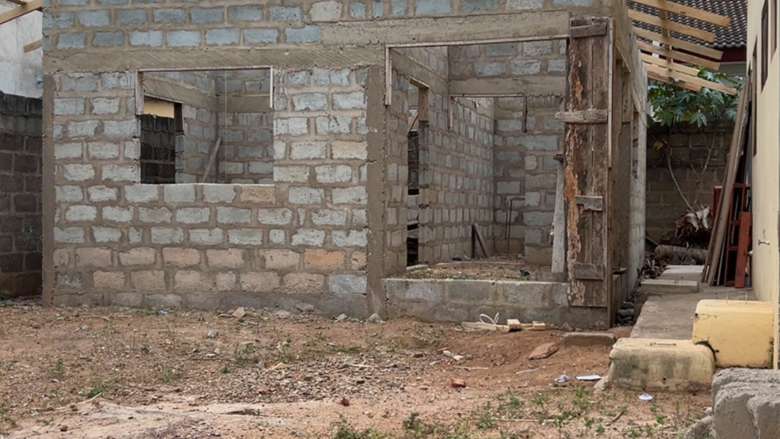 An unfinished house at blockwork stage, walls up and roof timbers exposed