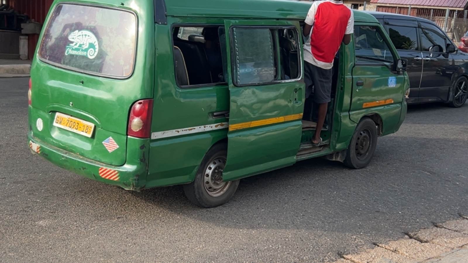 A green trotro minibus picking up passengers at the roadside